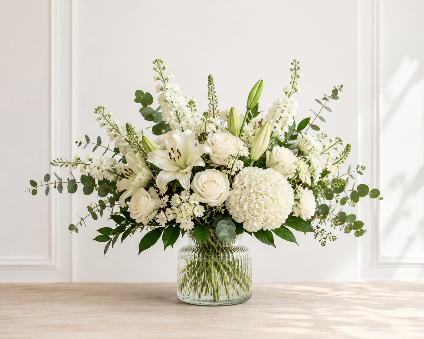 Elegant white lily and rose arrangement in a ribbed glass vase by Honeybear Flowers